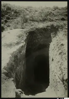 Tomb 11 at Marion during excavation, a deep cut dromos leading to a dark tomb opening