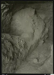 Tomb 9 at Marion during excavation, with a rounded earth face and loose stones on the slope