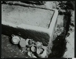 Tomb 15 at Marion during excavation, with pottery vessels lying beside a stone-edged structure