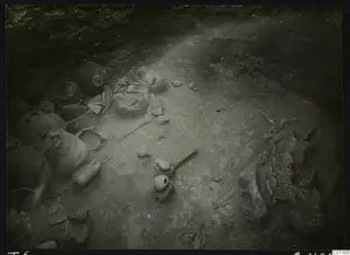 Tomb 6 at Marion during excavation, with broken pots and a skeleton on the floor of the chamber
