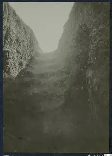 Deep excavation trench at Marion, Tomb 25, with stepped ground and stones along its sides