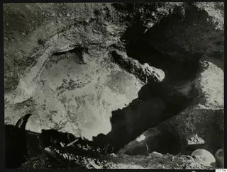 Tomb 14 at Marion during excavation, showing the rock-cut cavity with stones and rounded objects at the edge