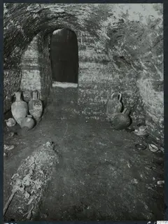 Interior of Tomb 22 at Marion, with jugs and bowls on the floor and skeletal remains at the lower left