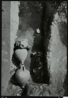 Tomb 14 at Marion during excavation, with pottery vessels standing and lying in a narrow cut in the earth.