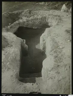 Tomb 15 at Marion: excavated dromos with steps descending between earth banks, a seated person at upper right