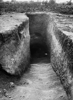 Tomb 25 at Marion: a stepped dromos leading down to the dark tomb entrance between cut earth walls.
