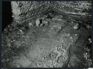 Interior of Tomb 22 at Marion, with pottery vessels on the floor and a partly exposed skeleton in the lower right.