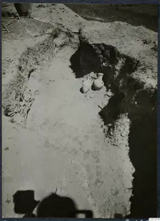 Tomb 45 at Marion: excavated cut with two pale pottery vessels standing at its far end