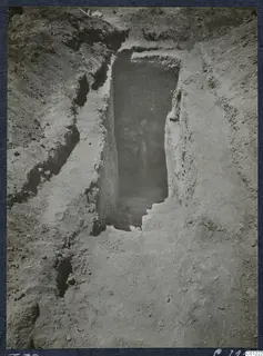 Tomb 39 at Marion during excavation: a rectangular shaft cut into soil leads down to a dark tomb entrance.