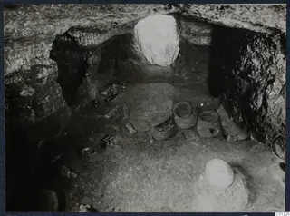 Tomb 36 at Marion during excavation, with vessels and small objects on the rock-cut chamber floor.