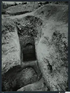 Excavated dromos leading down to an arched tomb entrance at Marion, its opening filled with stacked stone blocks.