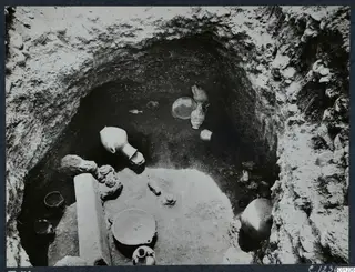 Tomb 56 at Marion during excavation, with pottery vessels and stones lying on the floor of the cut.