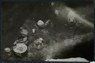 Tomb 43 at Marion, excavated floor with pottery vessels and stones lying in the soil
