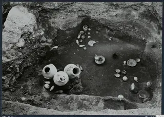 Tomb 44 at Marion during excavation, with pottery vessels and small objects lying on the floor of the cut.