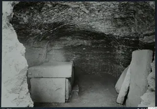 Interior of Tomb 34 at Marion, a rock-cut chamber with a stone sarcophagus under a flat slab lid.