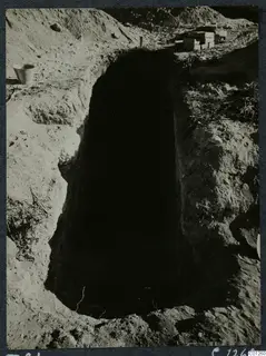 Tomb 21 at Marion during excavation, a deep rectangular cut with a bucket and stacked boxes at its edge