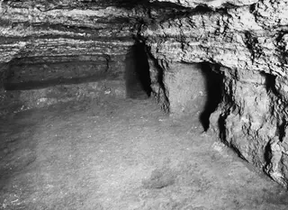 Interior of Tomb 25 at Marion, showing a rock-cut chamber with a niche and a sloping floor.