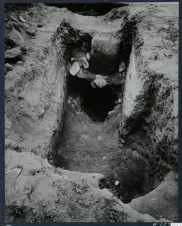 Excavation of Tomb 47 at Marion, showing a sloping cut with stones and a dark opening at its far end