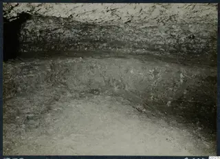 Interior of rock-cut Tomb 33 at Marion during excavation, with rough rock walls and a dusty floor
