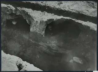 Tomb 31 at Marion during excavation, with two vessels in hollows in the cut wall and stones on the floor