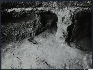 Interior of Tomb 39 at Marion during excavation, showing a rock-cut opening and a ledge along the wall.