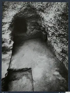 Tomb 61 at Marion during excavation, looking along a rock-cut passage toward a dark opening at the far end.