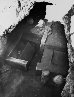 Interior of Tomb 53 at Marion, with stone benches along the chamber walls and pottery vessels on the floor and ledges.