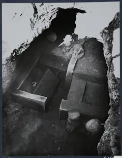 Interior of Tomb 53 at Marion, with stone slabs and several vessels inside a rock-cut chamber.