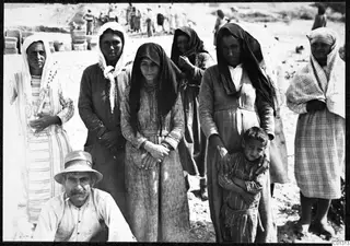 Women in headscarves and a man in a straw hat posing before the excavation at Marion