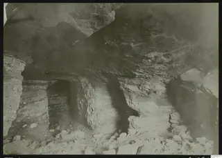 Interior of Tomb 2 at Marion, showing rock-cut walls, a low ceiling and stones scattered across the floor.