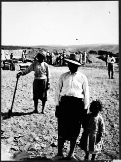 Workers from the excavation at Marion with a child in the foreground, with a group of people and hills behind