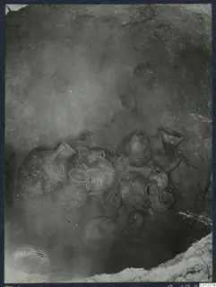 Pottery vessels clustered on the floor of Tomb 95 at Marion, photographed in situ.