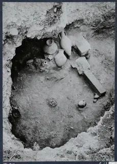 Tomb 73 at Marion during excavation, with pottery vessels and stone slabs lying in situ.