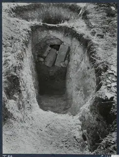 Excavation of Tomb T.88 at Marion, with flat stone slabs over an opening at the bottom of the cut