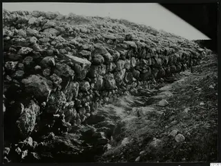 Rough stone wall at Nitovikla, with an excavated path or cutting running along its foot.