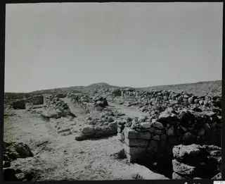 Excavated stone walls at Nitovikla on dry, open ground with low hills behind.