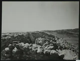 Excavated stone walls at Nitovikla on the Karpas Peninsula, with rubble and a sea view beyond