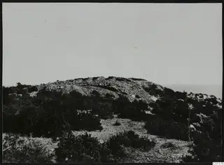 Low rocky hill with scrub and stone walling along its crest, with the sea visible beyond at Nitovikla, Karpas peninsula.