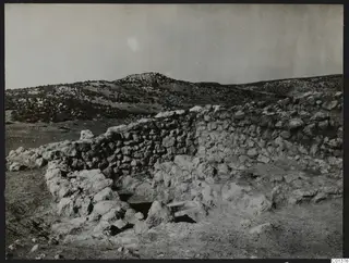Stone wall and rubble with a rocky hill behind, at Nitovikla on the Karpas Peninsula