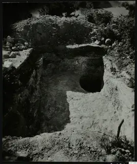 Excavation cutting at Nitovikla on the Karpas Peninsula, with a round dark opening in the far wall