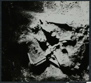 Skeleton in Tomb 14 at Ayios Iakovos during excavation, with rib and long bones lying in packed soil.