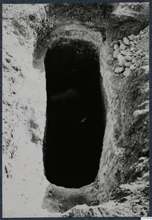 Tomb 13 at Ayios Iakovos during excavation, seen from above as a dark rectangular opening in pale soil