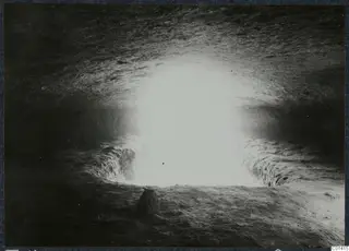 Tomb chamber at Ayios Iakovos during excavation, lit from an opening in the rock-cut wall