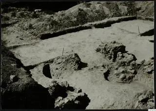 Excavation at Ayios Iakovos with pale floor surfaces, stone heaps and marker stakes