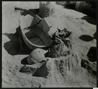 Excavated ground at Ayios Iakovos with a broken clay vessel and scattered sherds in situ