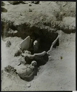 Excavated pit at Ayios Iakovos with a broken pottery jar, standing stone slabs and skulls in the soil