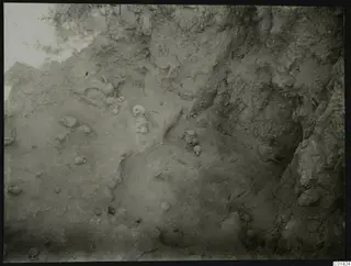 Excavation at Nitovikla with small vessels and stones lying in situ on a pale sloping surface