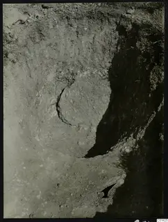Excavation cutting at Kountoura Trachonia with a curved soil face, dark shadowed walls and scattered stones