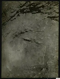Excavation at Kountoura Trachonia, with a pale flat stone visible in the earth wall of the cut.