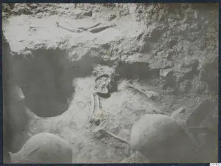 Tomb chamber at Ayios Iakovos during excavation, with bones and rounded objects set in the soil